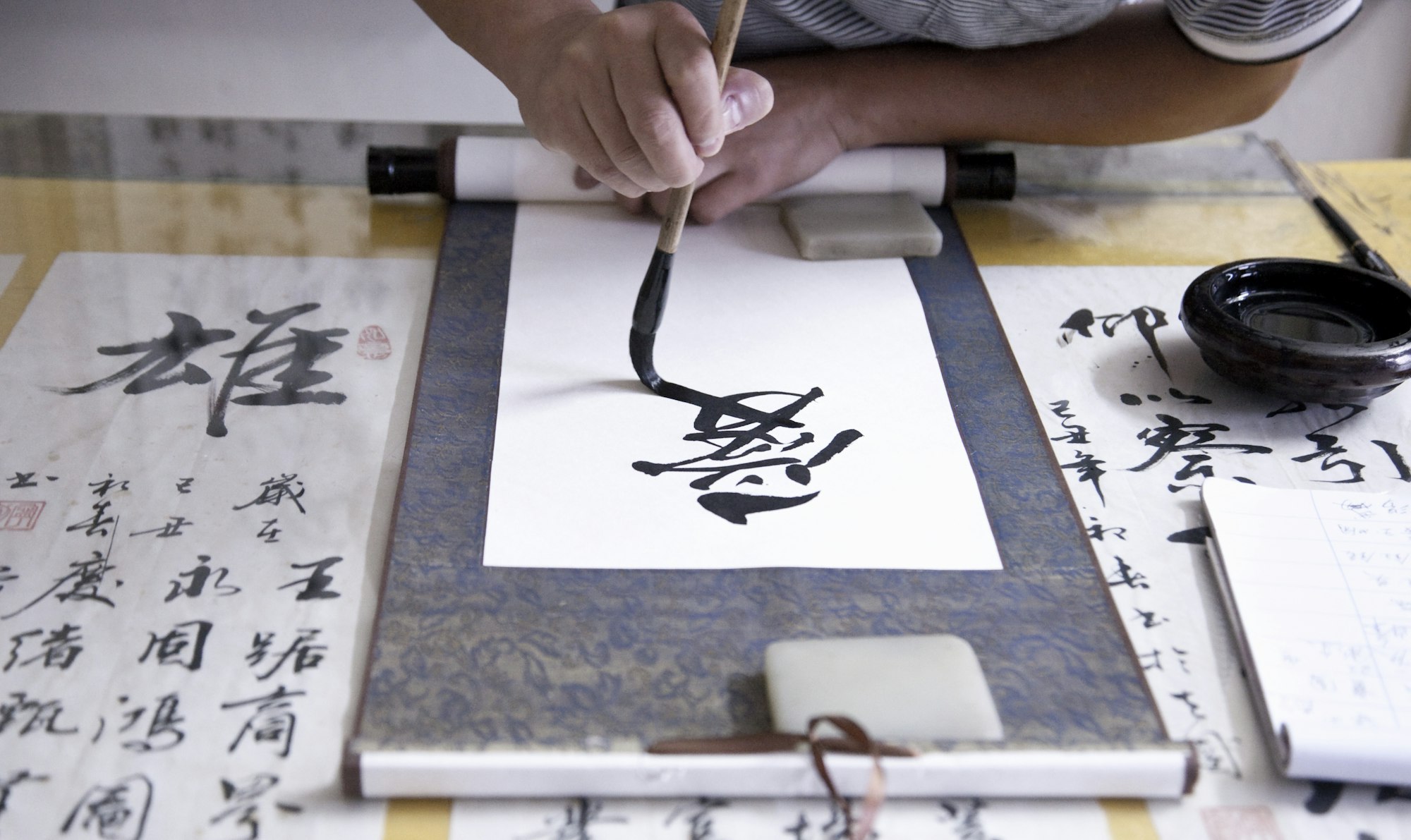 Calligrapher writing Chinese symbols on scroll