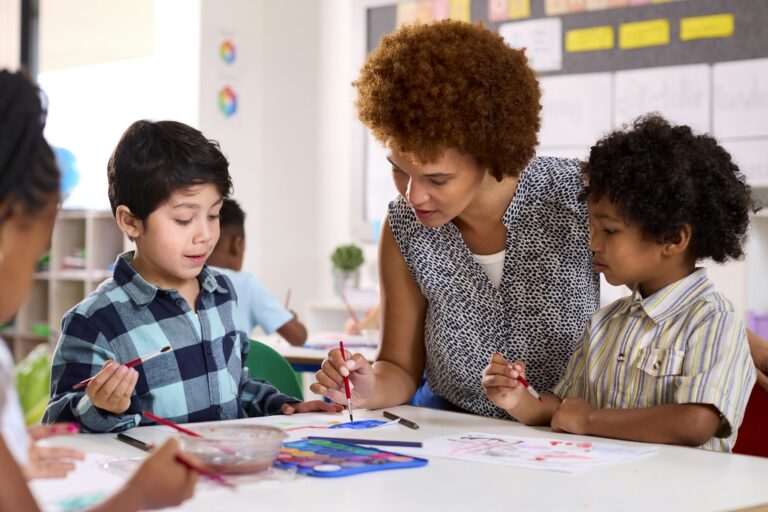 Female Teacher With Multi-Cultural Elementary School Pupils In Art Class At School